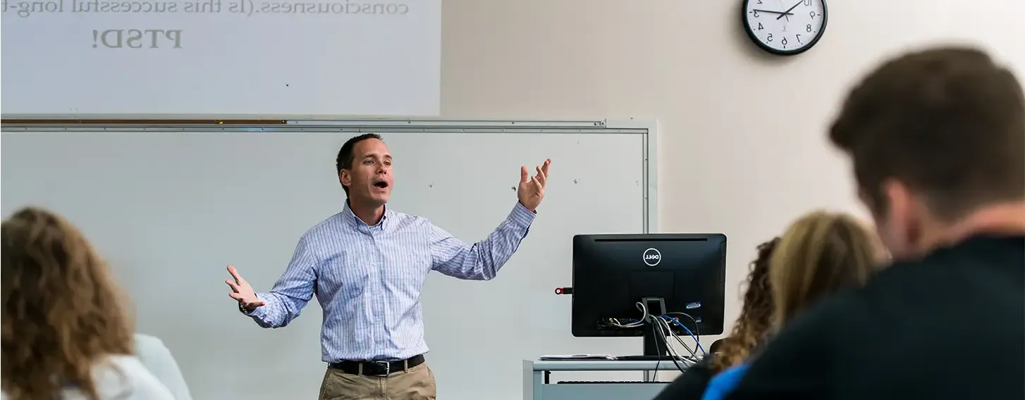 A man teaching in a classroom filled with attentive students.